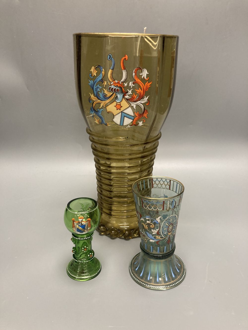 A large German historismus enamelled glass humpen, 30cm and two similar glasses